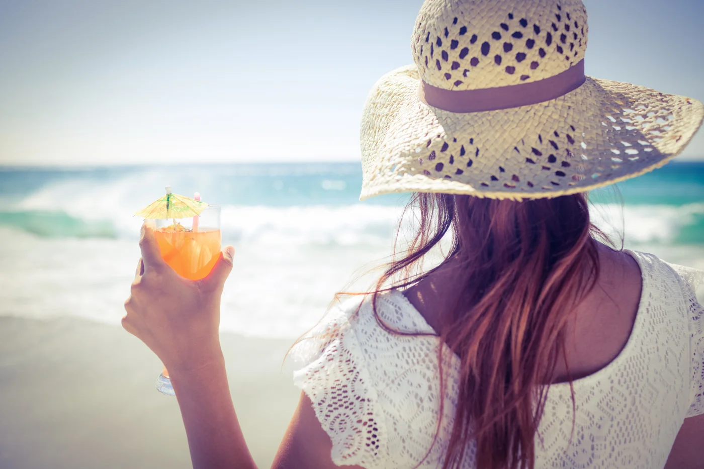 Eine Frau am Strand mit einem Drink in der Hand