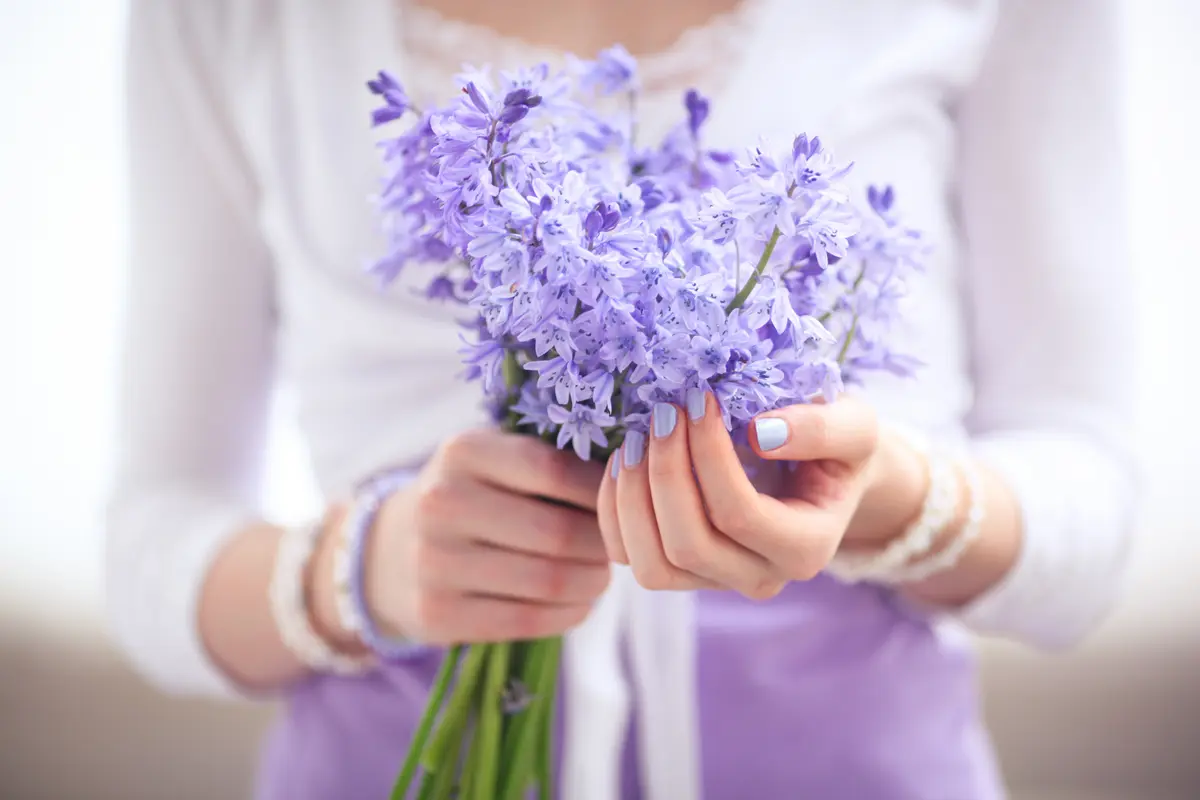 Mädchen mit lila Nagellack hält Blumen