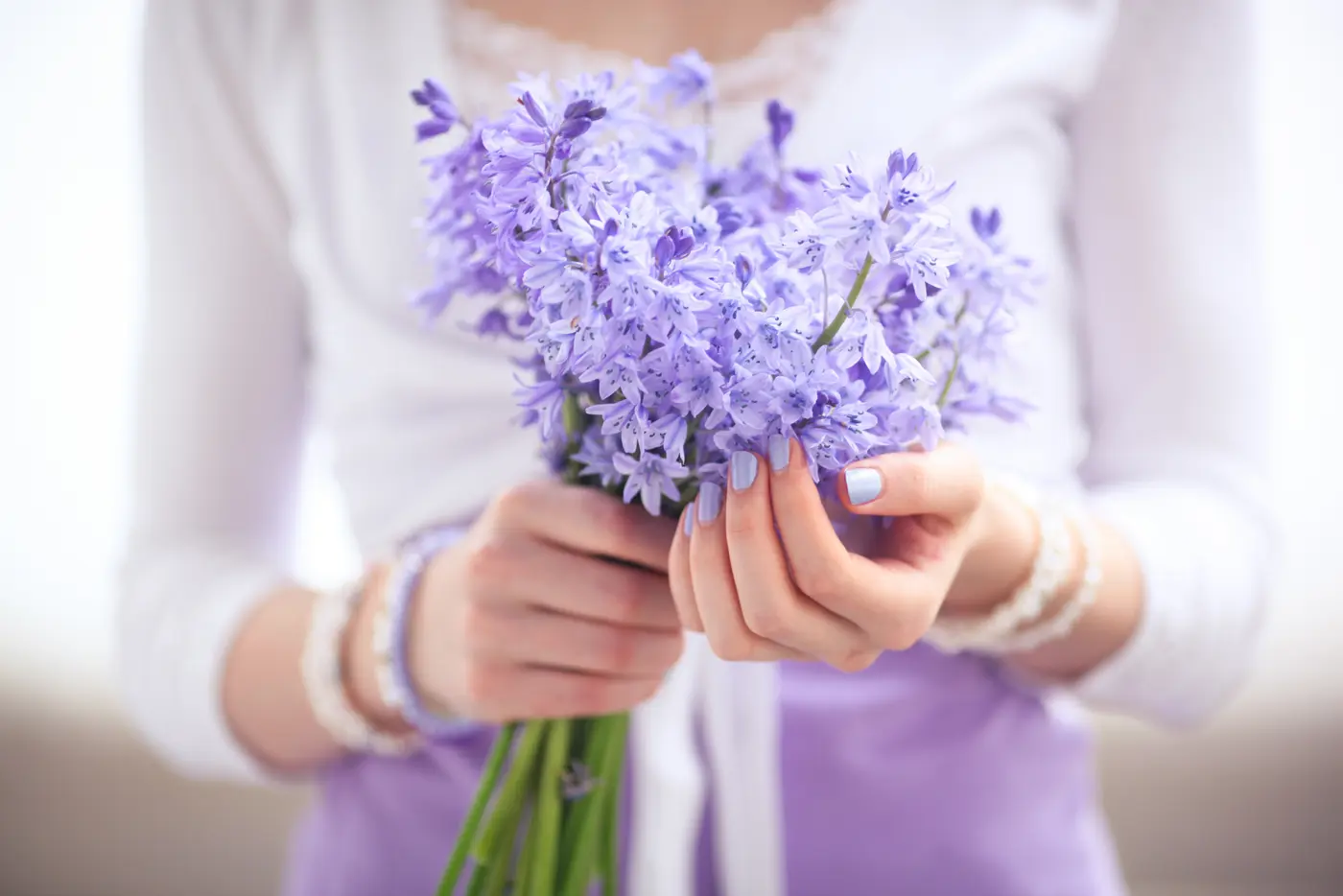 Mädchen mit lila Nagellack hält Blumen