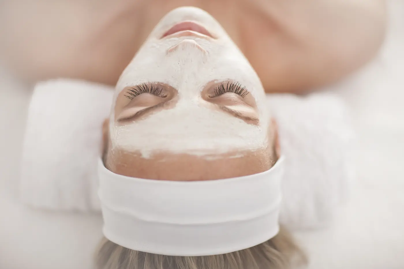 Frau mit Gesichtsmaske liegt im Spa auf einer Liege