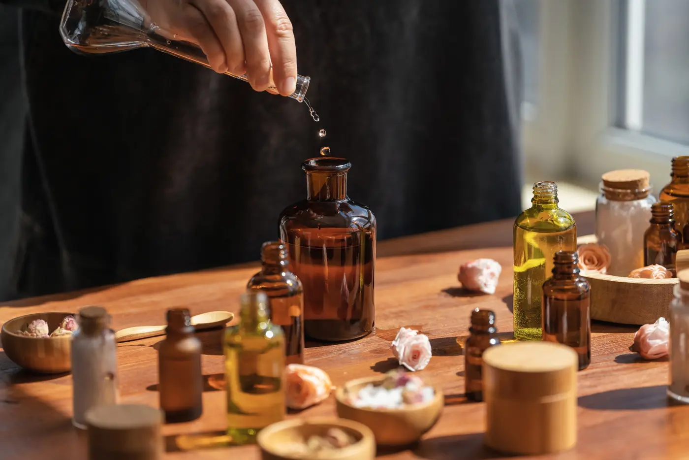 Parfumeurin bei der Arbeit an einem Tisch mit mehreren Glasflakons und Essenzen