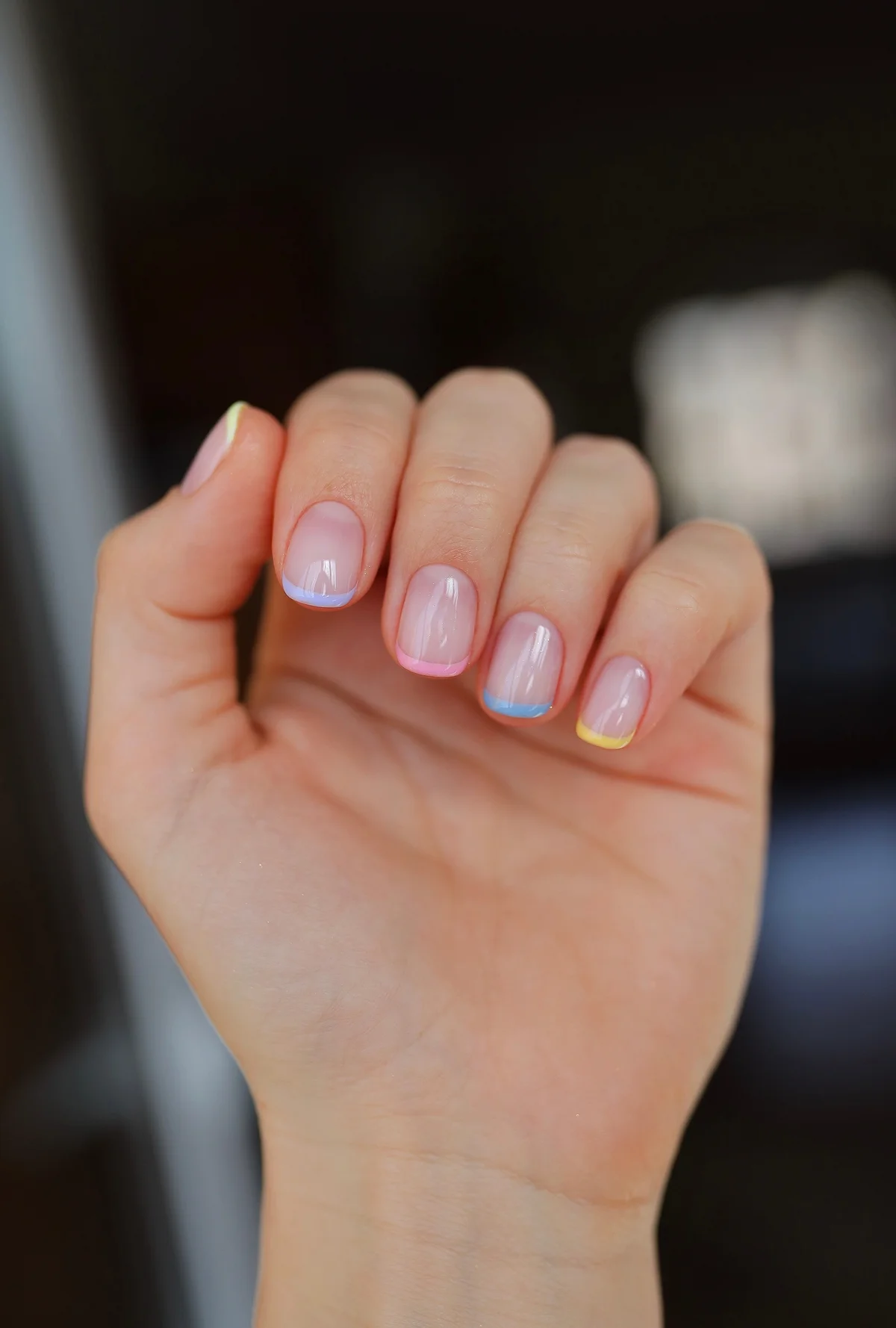 Bunte French Nail Maniküre an der Hand einer jungen Frau