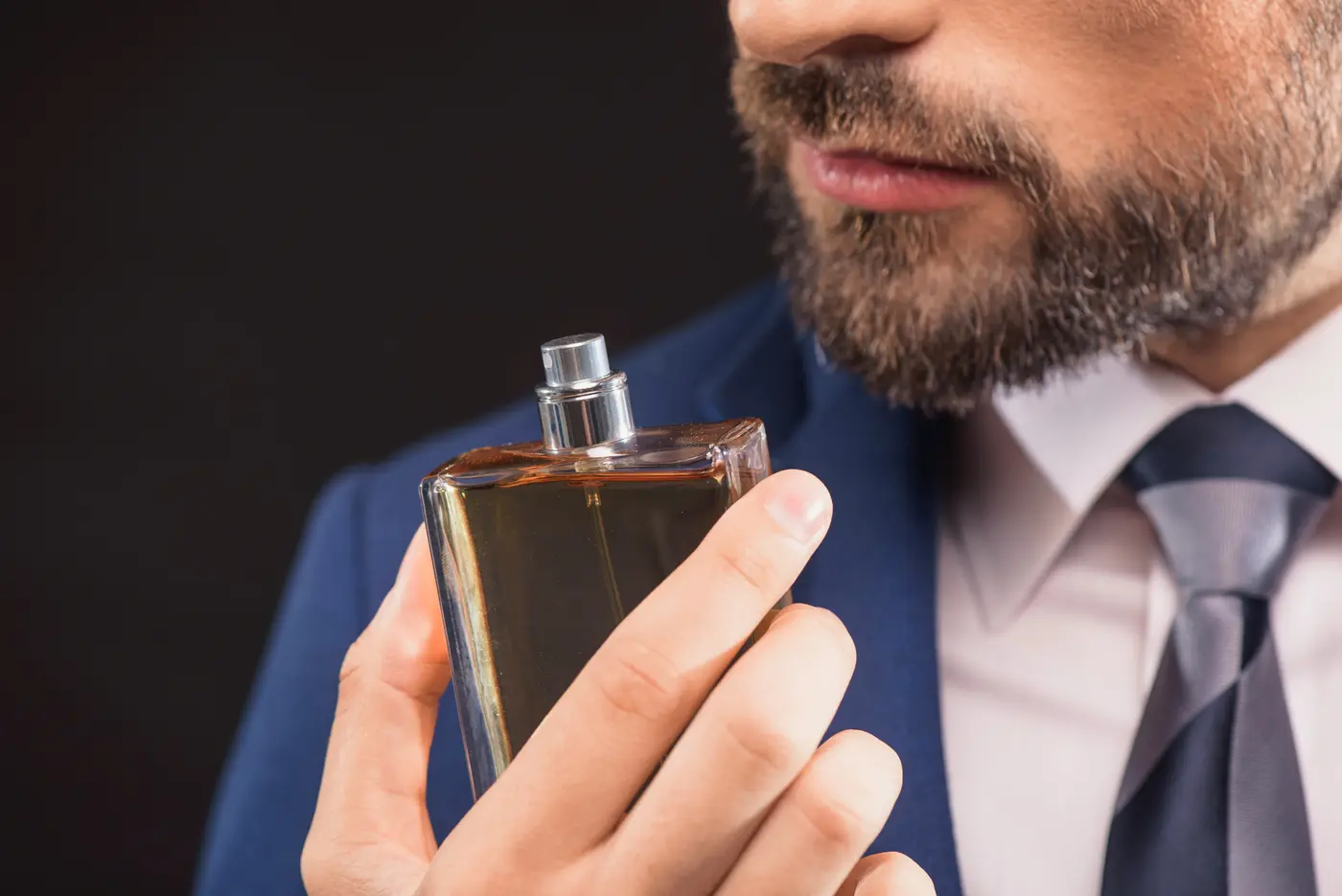 Mann im Anzug riecht an Parfum