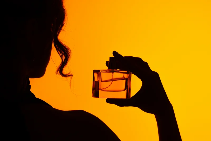 Schatten einer Frau mit Parfum in der Hand