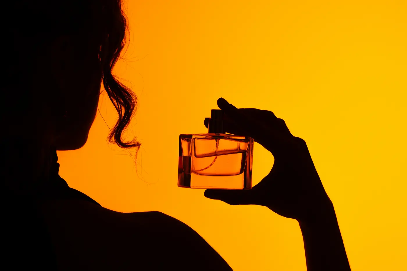 Schatten einer Frau mit Parfum in der Hand