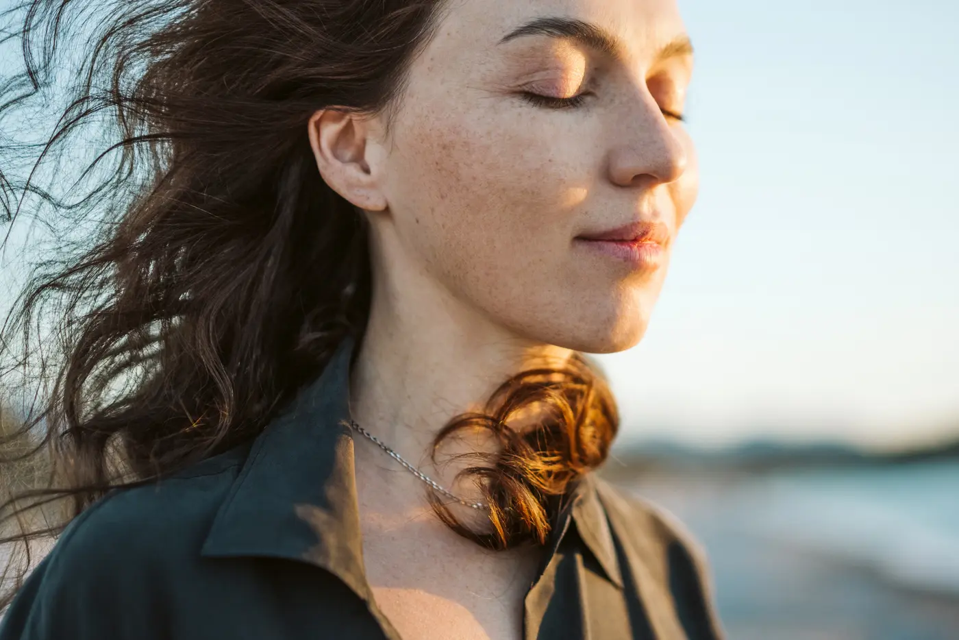 Frau mit Sommersprossen draußen bei Wind