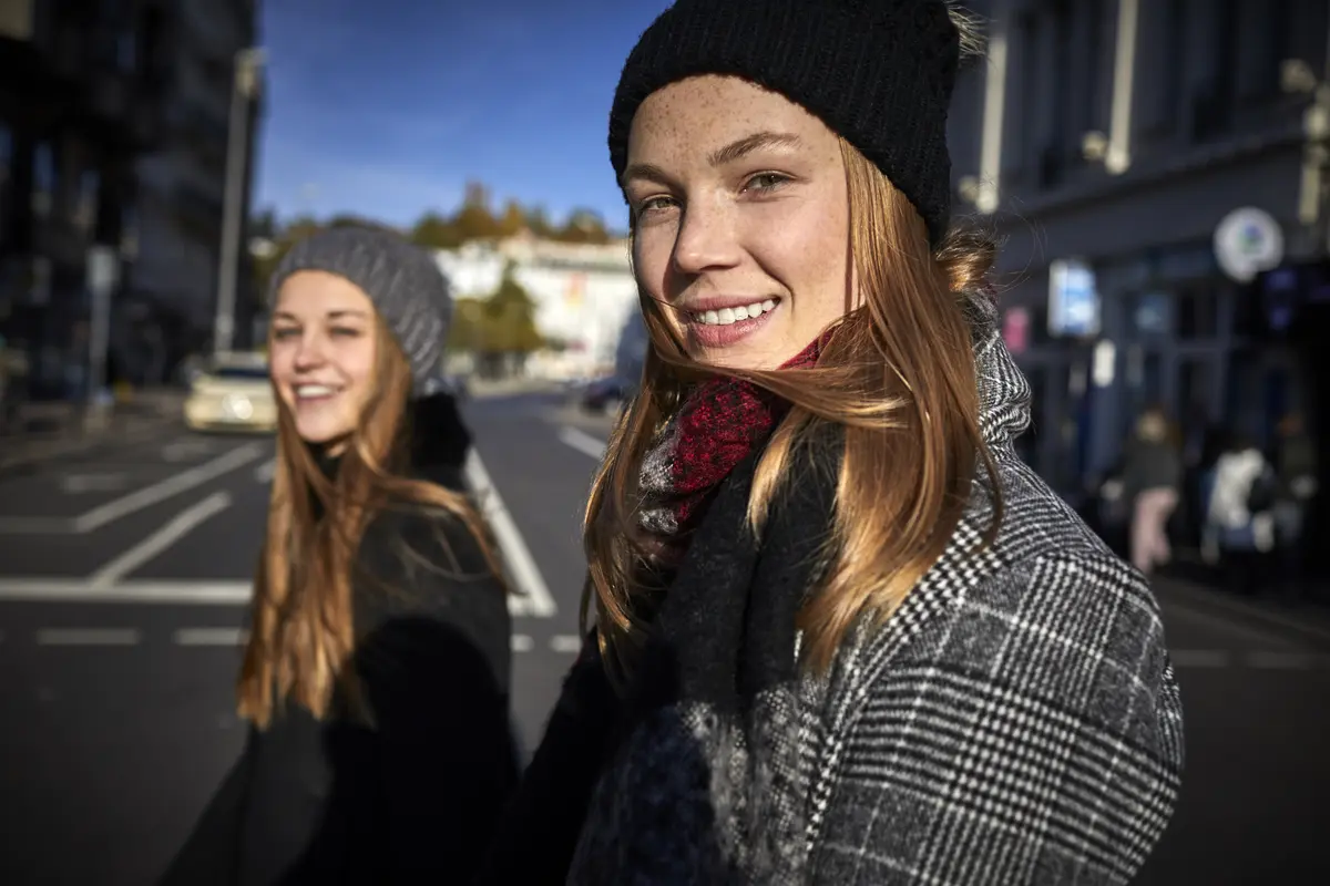 Zwei junge Frauen in Winterkleidung überqueren eine Straße