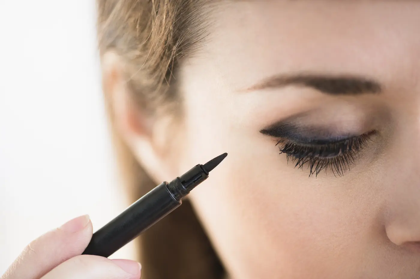 Junge Frau zieht ihren Eyeliner mit einem Eyeliner-Stift