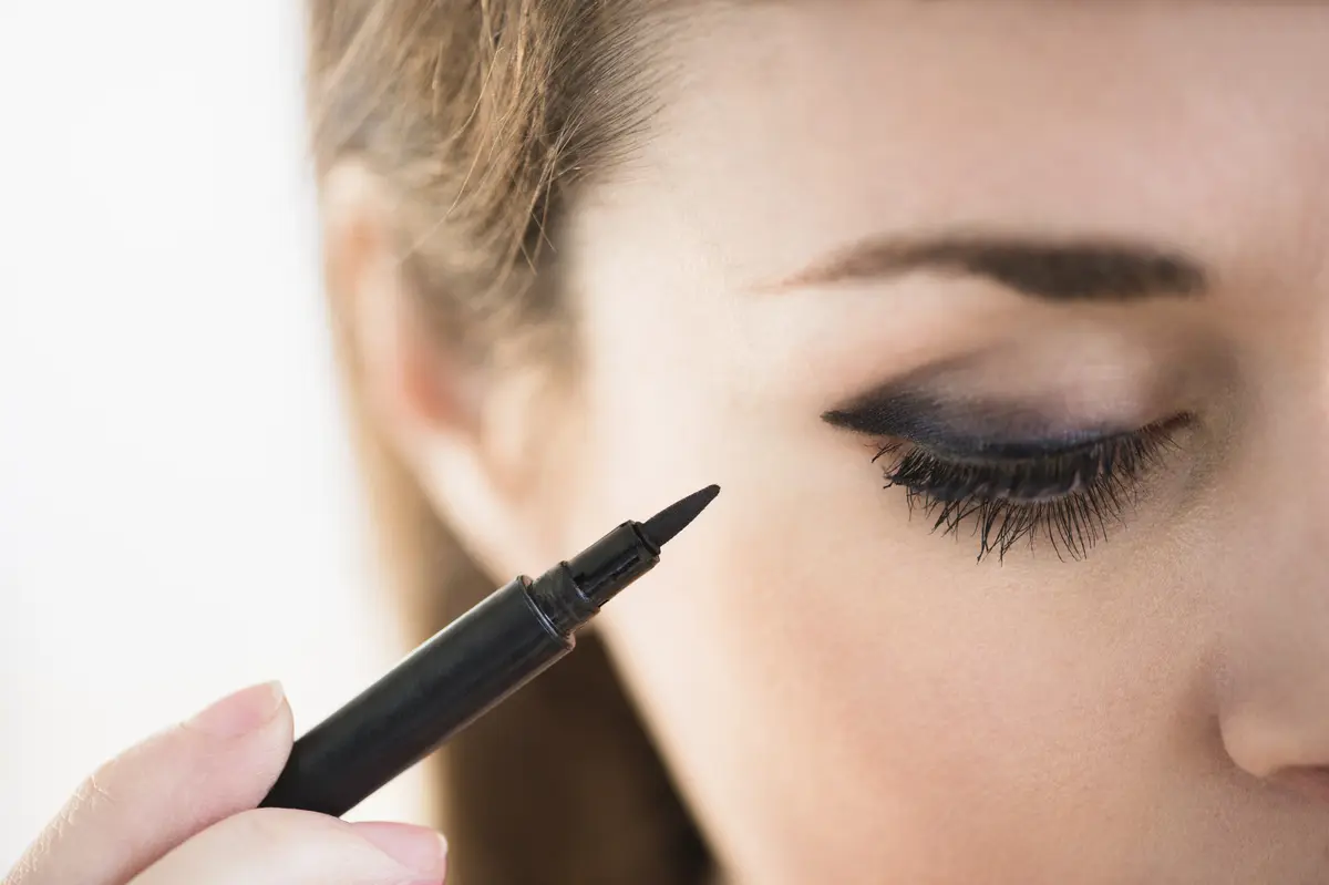 Junge Frau zieht ihren Eyeliner mit einem Eyeliner-Stift