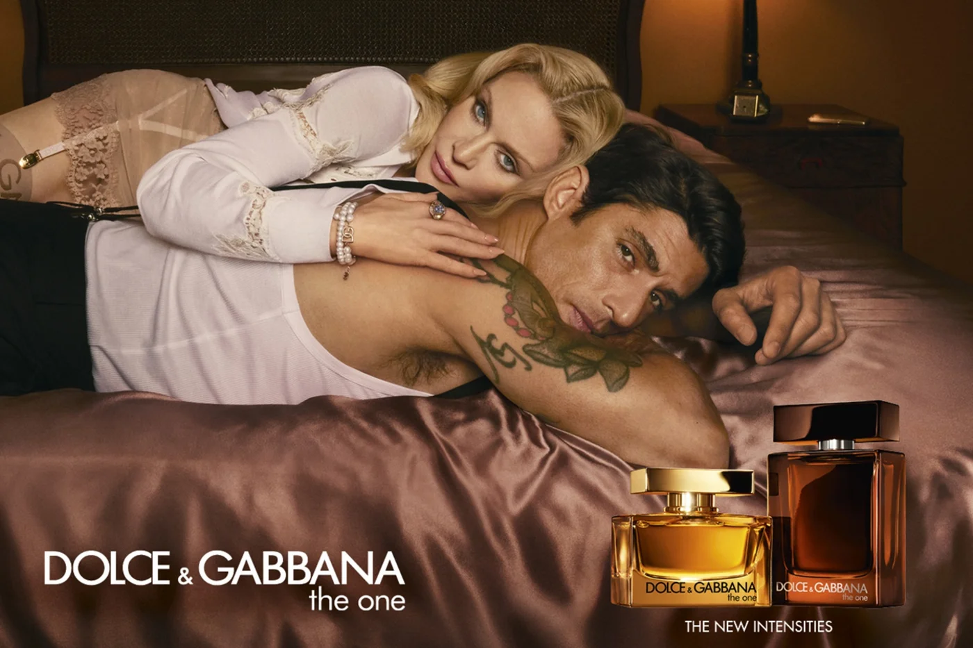 Kampagnenvisual Dolce&Gabbana The One, ein Pärchen (Mann und Frau) liegt auf einem Bett, sie verführerisch an ihn geschmiegt 