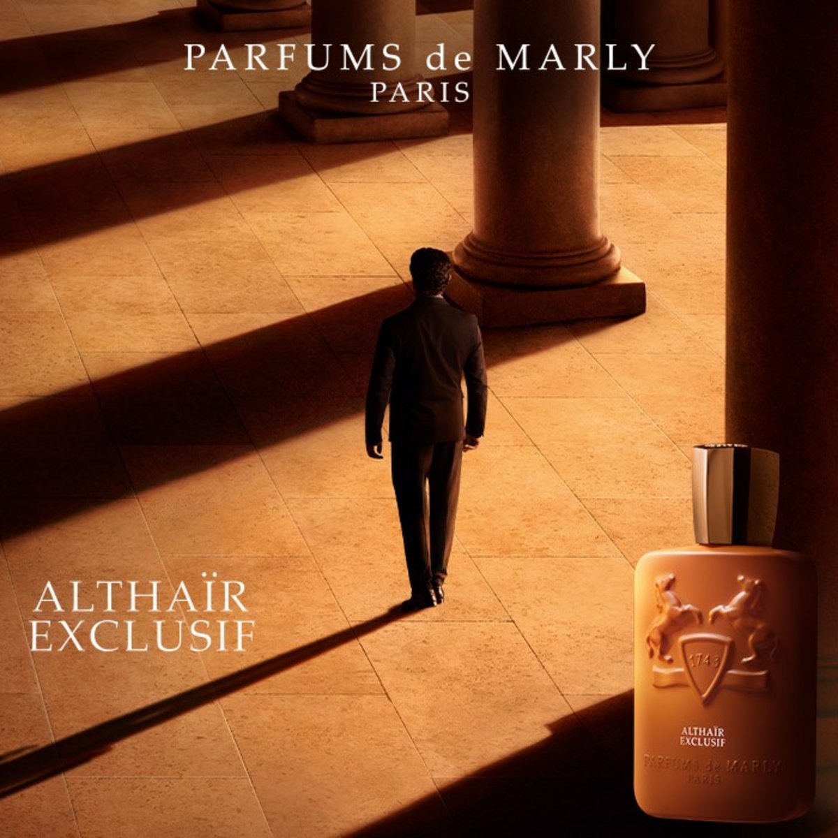 Parfums de Marly Althaïr Exclusif: Flakon in Cognacbraun vor einem Mann im Anzug, der durch eine sonnige Säulenhalle mit langen Schatten geht