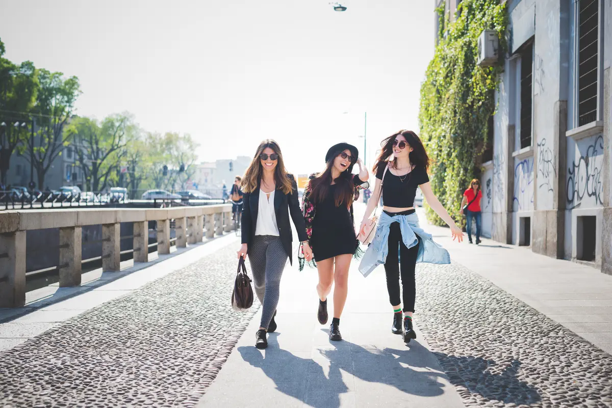 Drei Frauen laufen im Sonnenschein am Kanal entlang