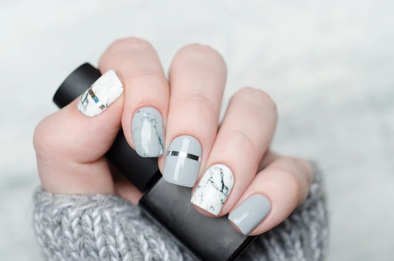 Hand mit Marmor Nägeln und Nagellack