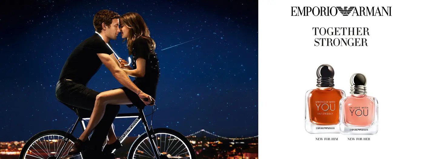 Liebespaar sitzt auf einem Fahrrad, daneben die zwei Emporio Armani Düfte