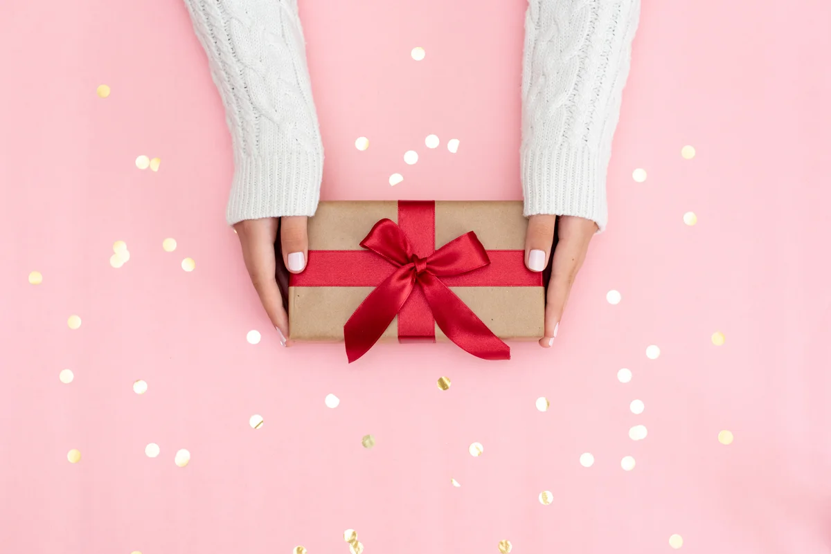 Frauenhände überreichen ein Geschenk