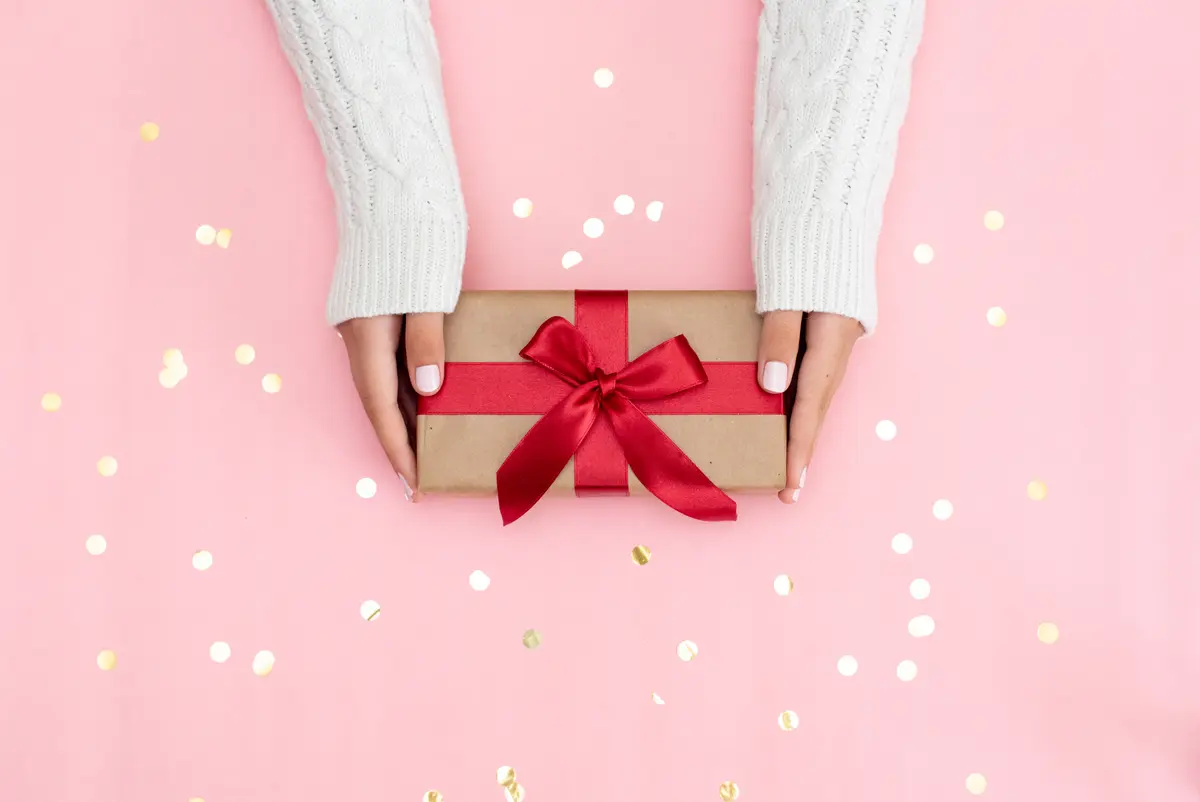 Frauenhände überreichen ein Geschenk