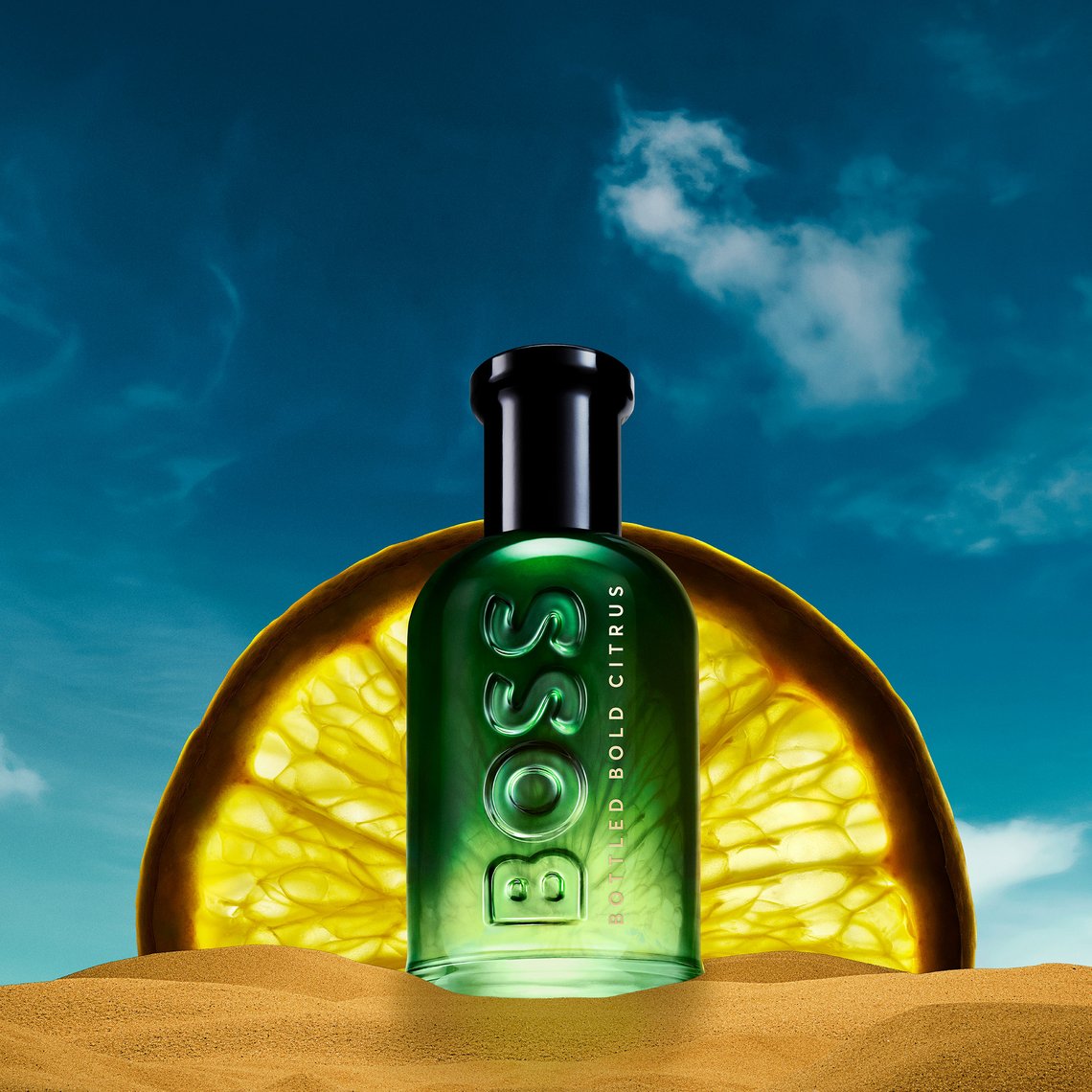 BOSS Bottled Bold Citrus - Flakon im Sand, dahinter überdimensionierte Zitronenscheibe