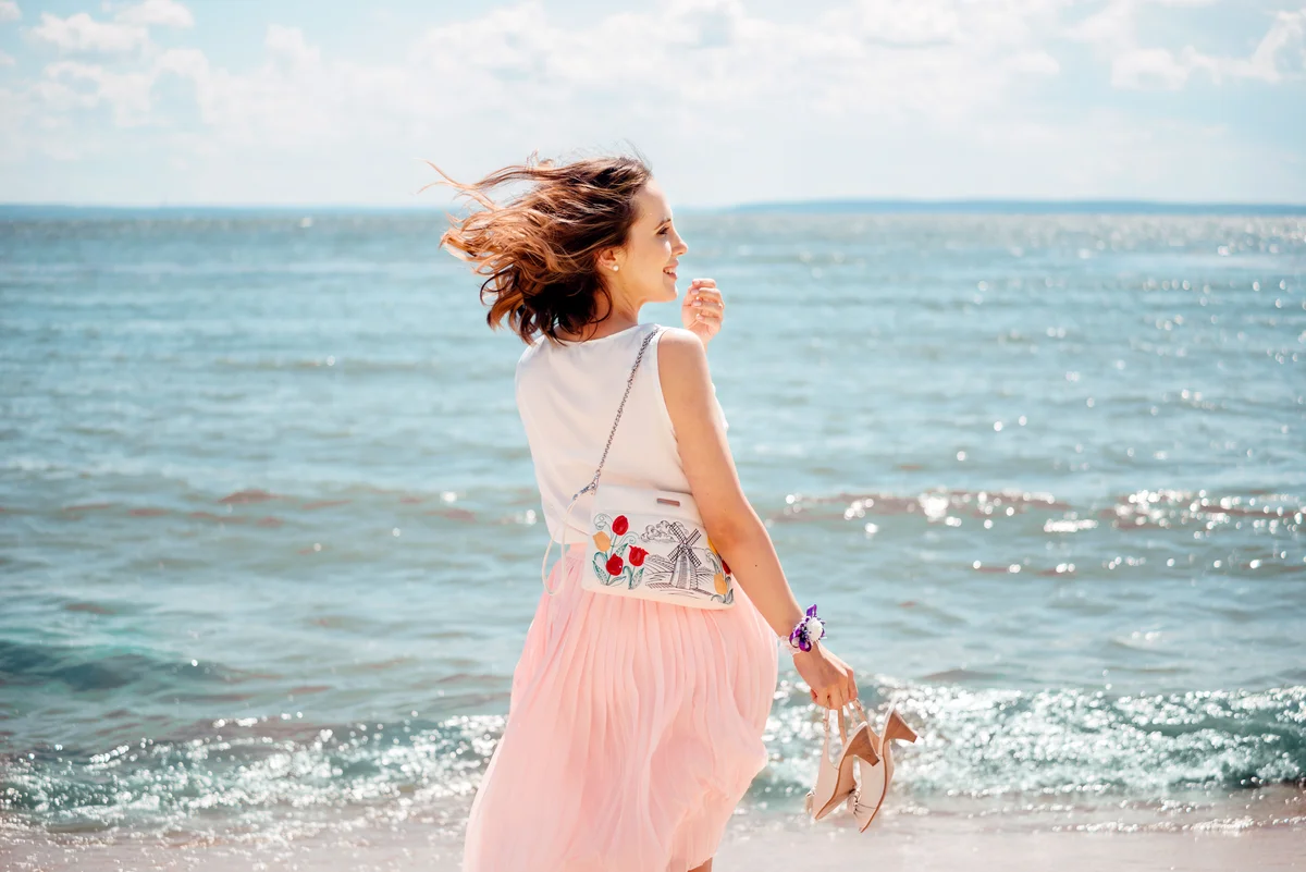 Frau im Sommer am Strand mit Wind im Haar