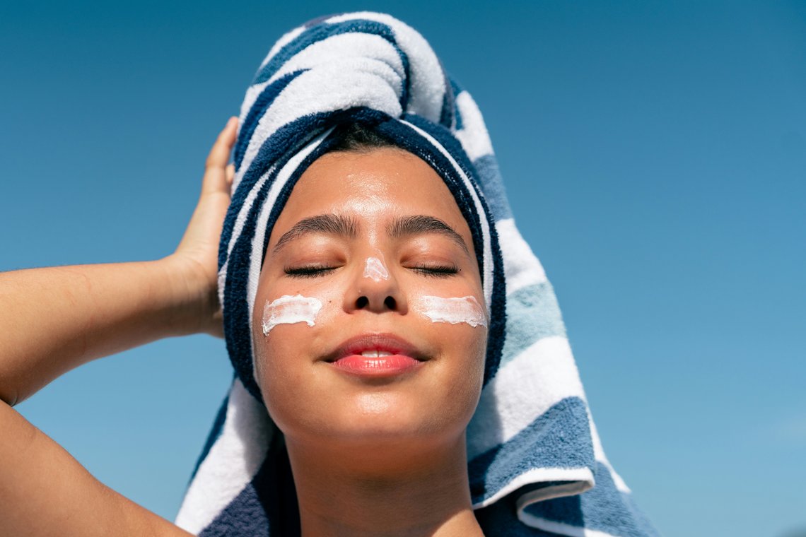 Frau mit Tuch auf dem Kopf und Creme im Gesicht vor blauem Himmel Frau mit Tuch auf dem Kopf und Creme im Gesicht vor blauem Himmel