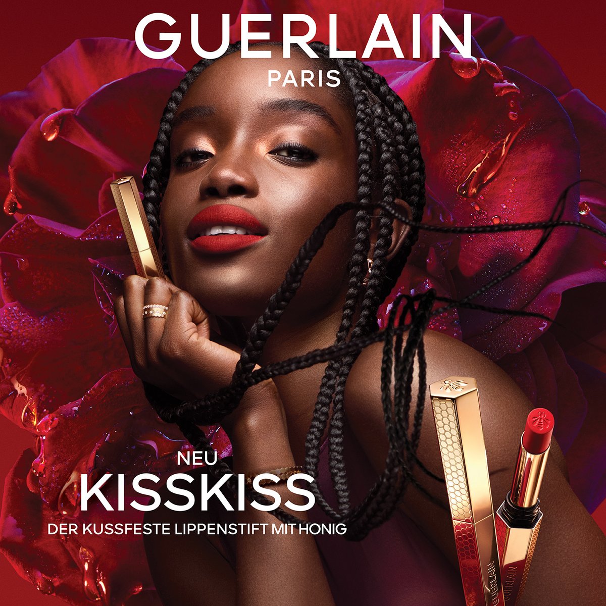 Guerlain KissKiss Werbebanner für den kussfesten Lippenstift mit Honig. Porträt einer Frau mit roten Lippen vor einer großen, dunkelroten Rose, flankiert von den goldenen Lippenstifthülsen.
