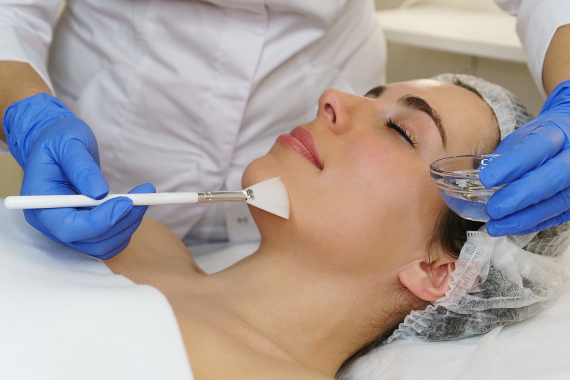 Kosmetikerin streicht Hyalurongel auf das Gesicht einer Patientin