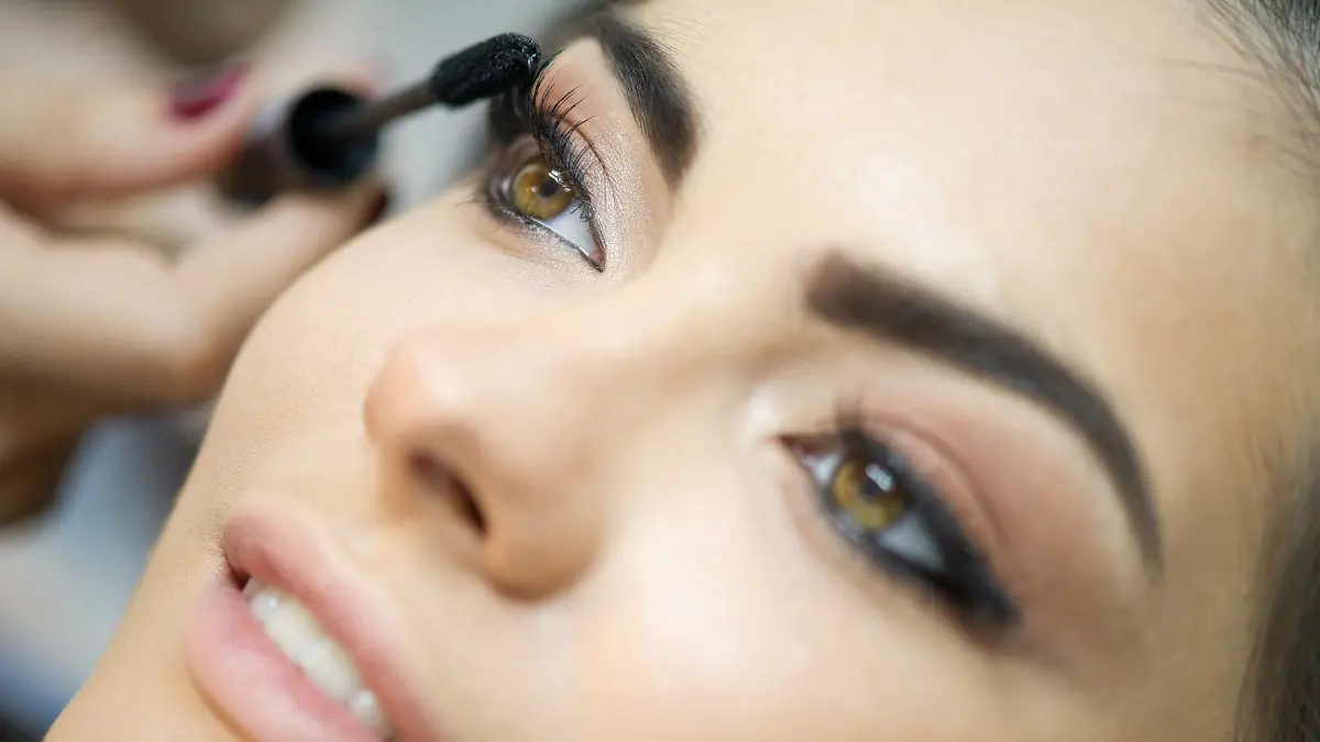 Eine Frau tuscht sich die Wimpern