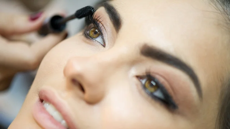 Eine Frau tuscht sich die Wimpern