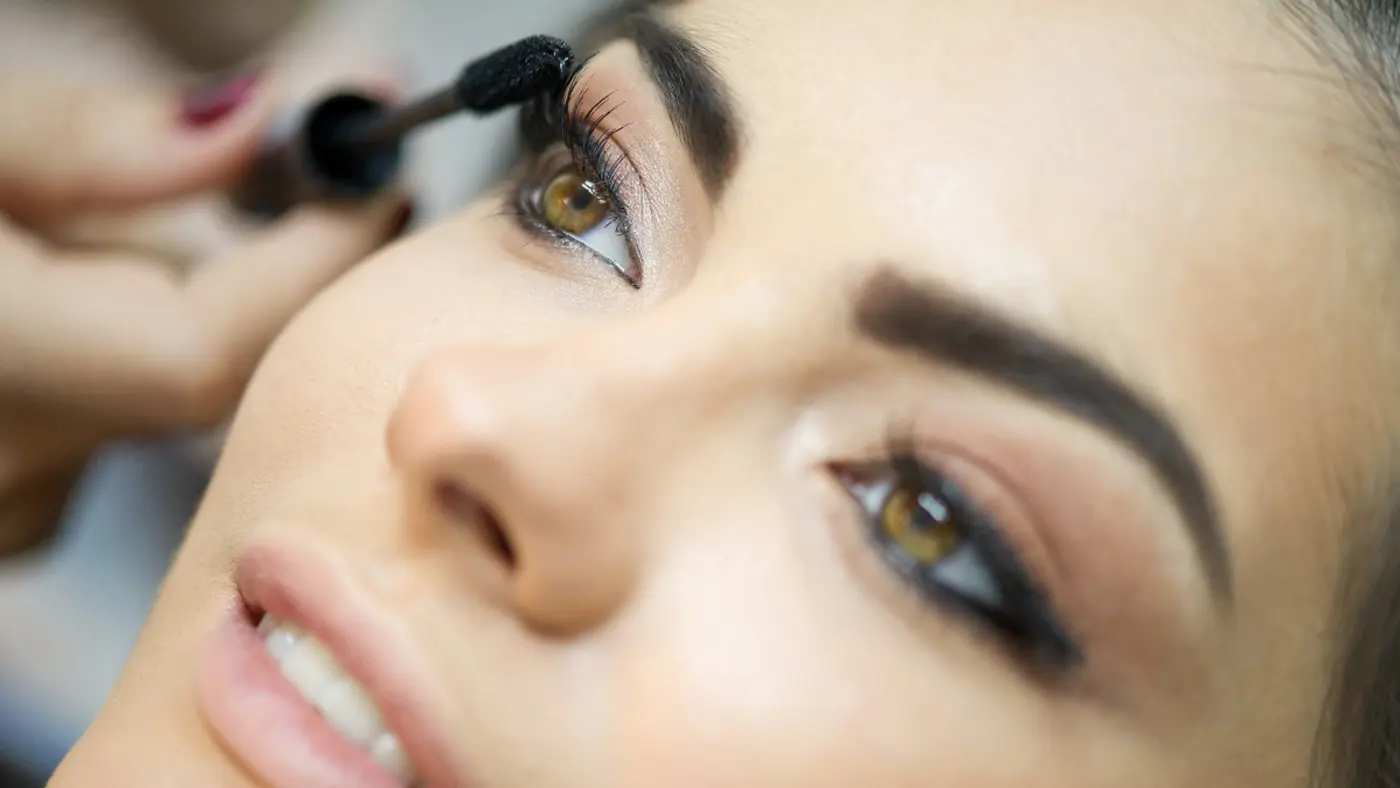 Eine Frau tuscht sich die Wimpern