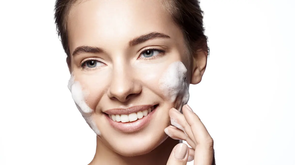 Frau reinigt ihr Gesicht mit Schaum