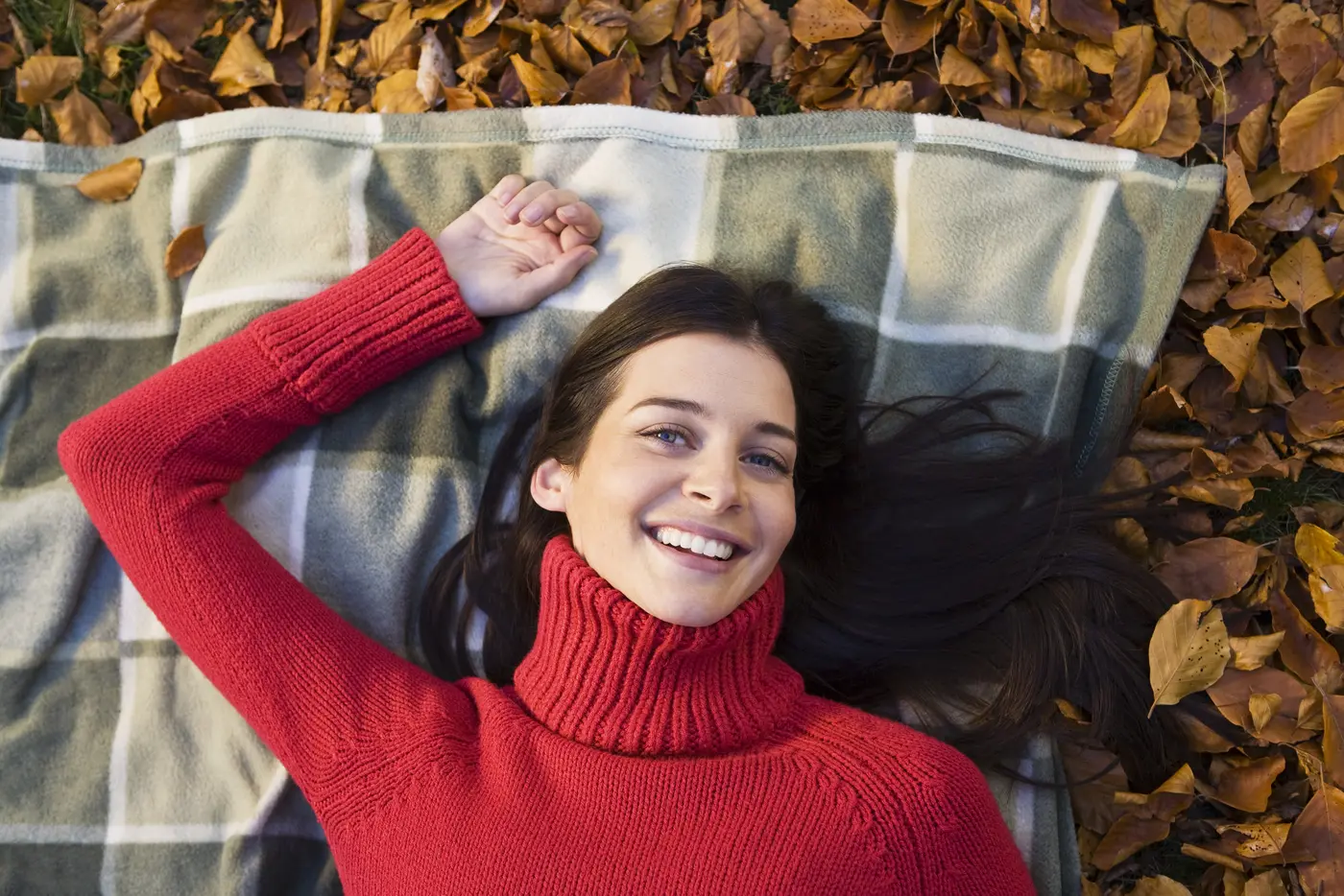 Frau liegt auf einer Decke im Herbstlaub