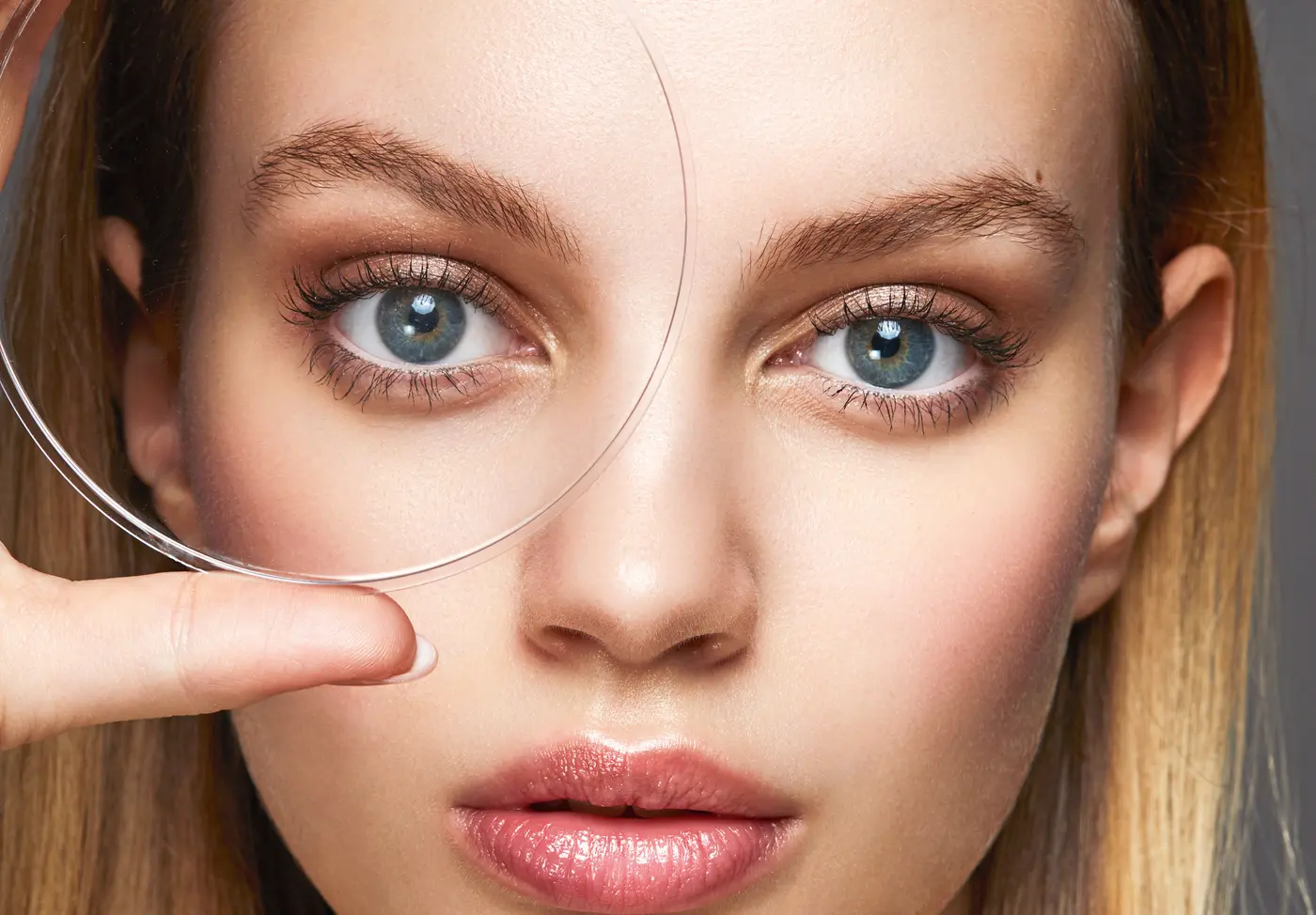 Blonde Frau mit Glas vor dem rechten Auge