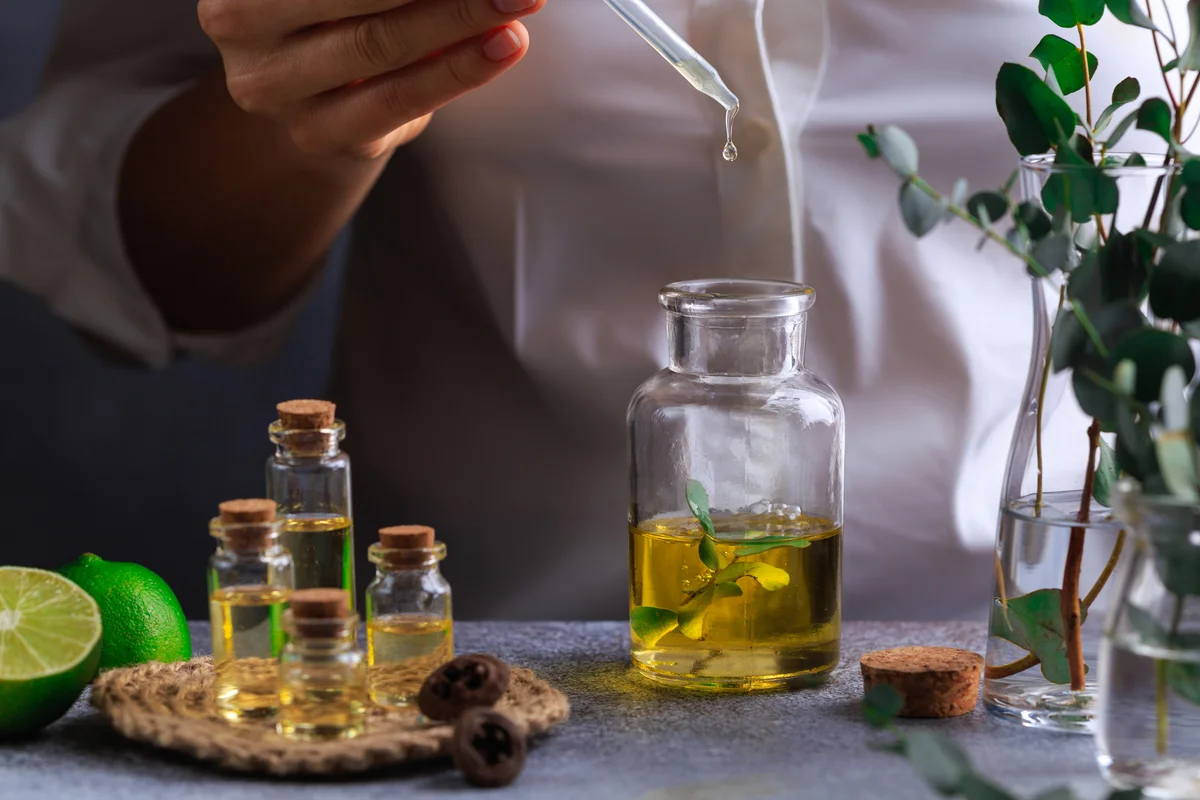 Tiegel und Gläser mit Flüssigkeiten und Kräuter für veganes Parfum
