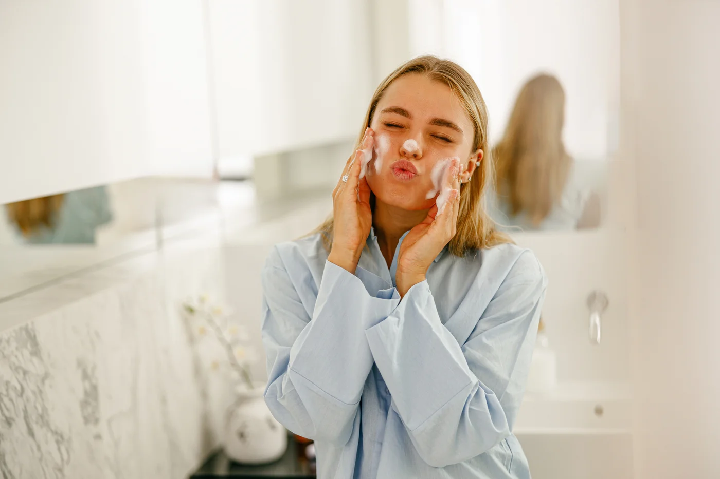 Frau mit Schaum im Gesicht im Bad