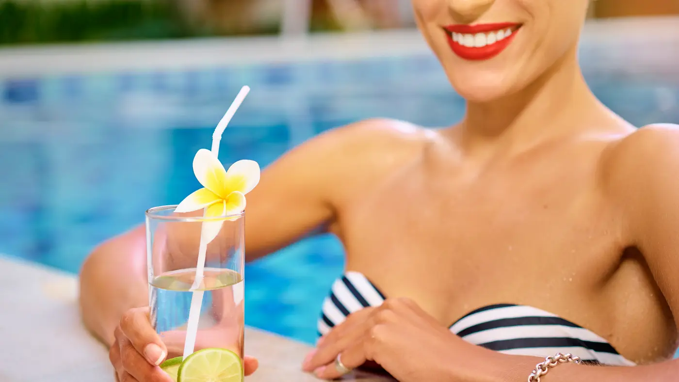 Eine Frau im Bikini lehnt über den Poolrand