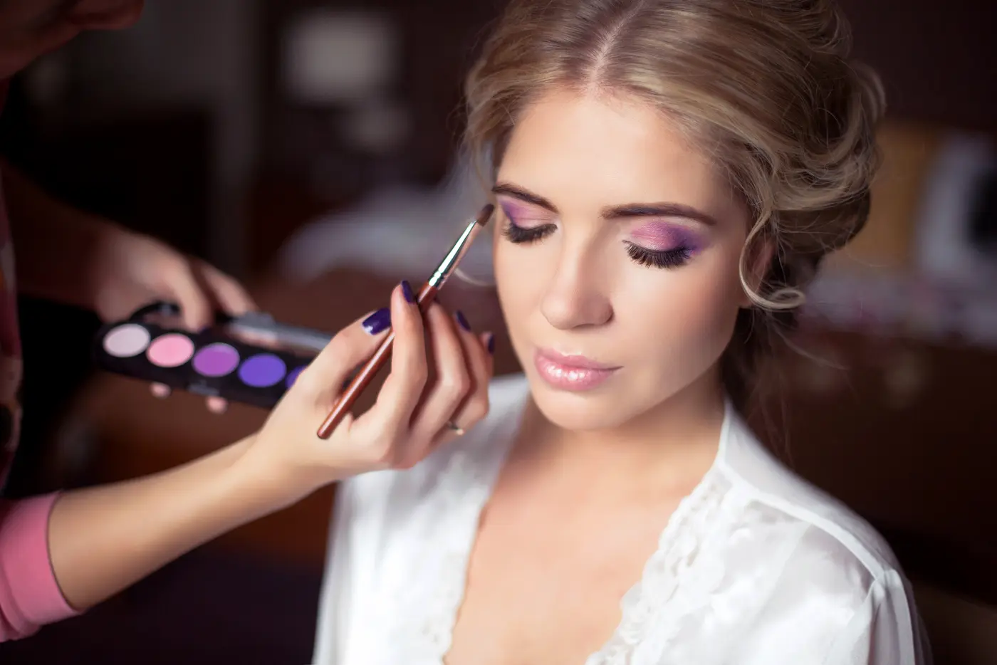 Mke-up Artist trägt Lidschatten bei Model auf