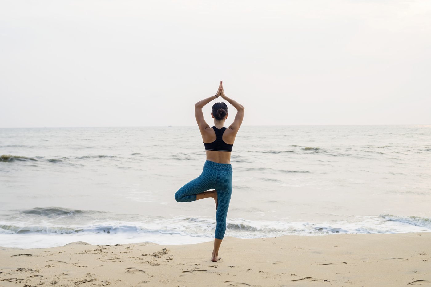 Frau macht Yoga am Strand