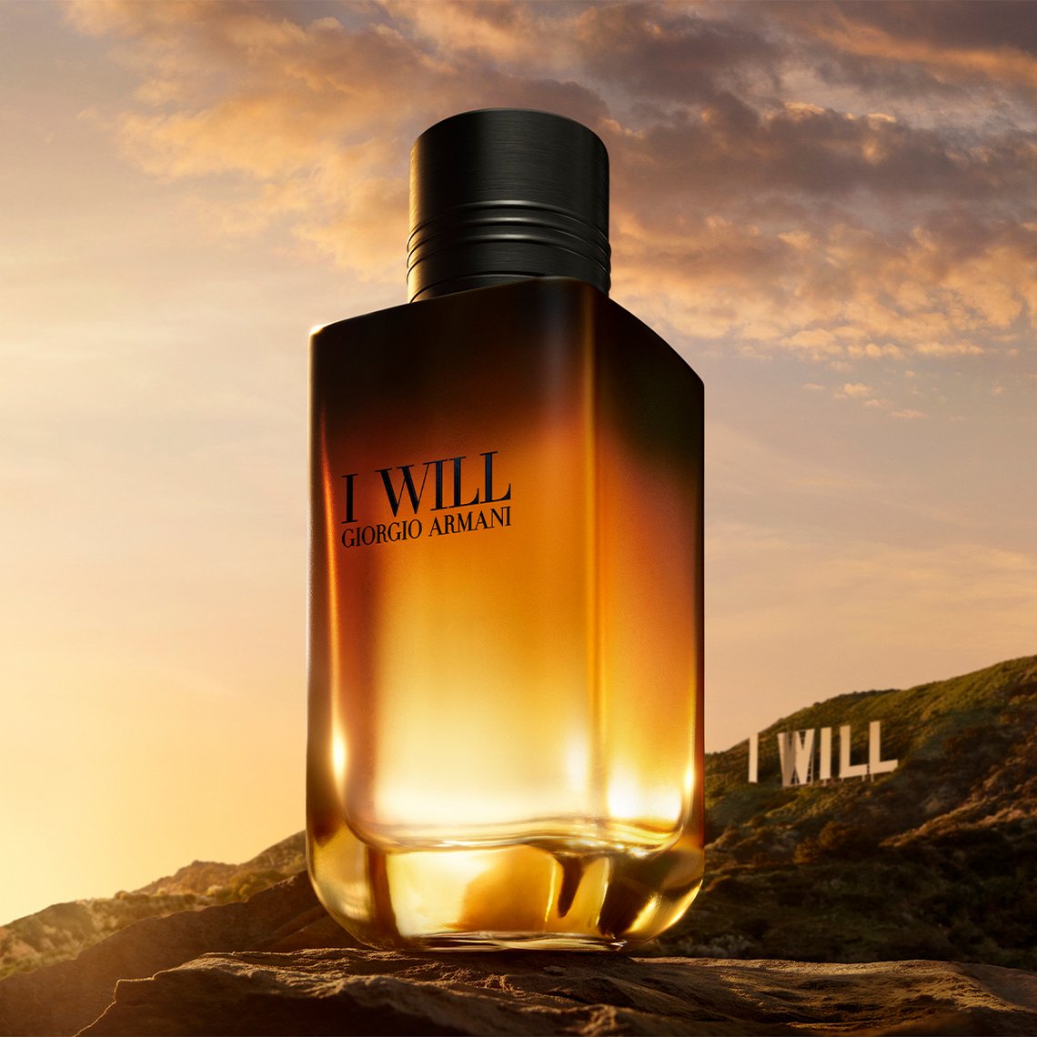 Giorgio Armani I Will Parfümflakon auf Felsen vor Hügellandschaft mit Hollywood-Sign-artigem 'I WILL'-Schriftzug im Sonnenuntergang