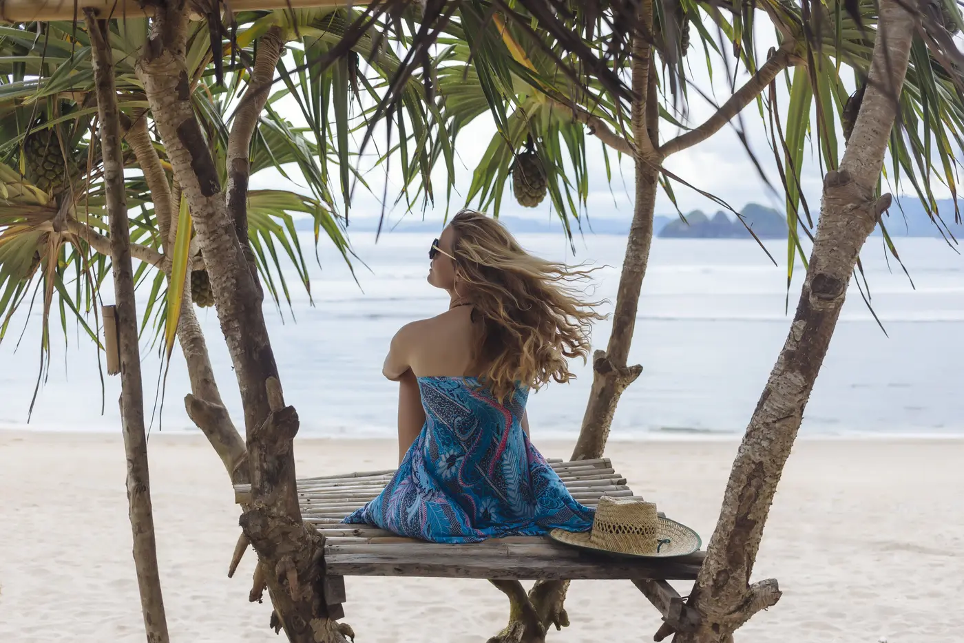 Frau sitzt am Strand und guckt aufs Meer