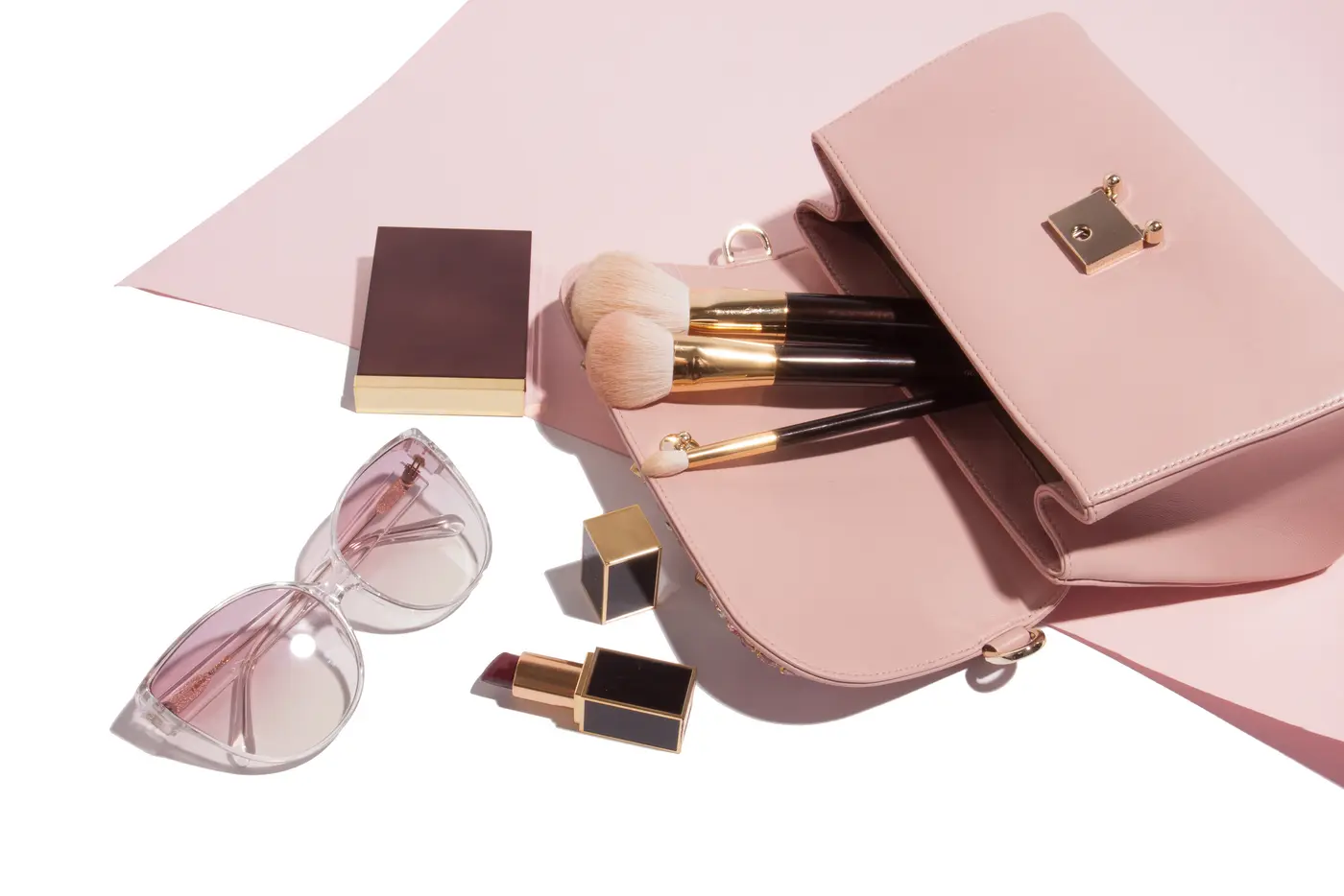 Rosa Handtasche mit Schminkpinseln, Handy, Lippenstift und Sonnenbrille