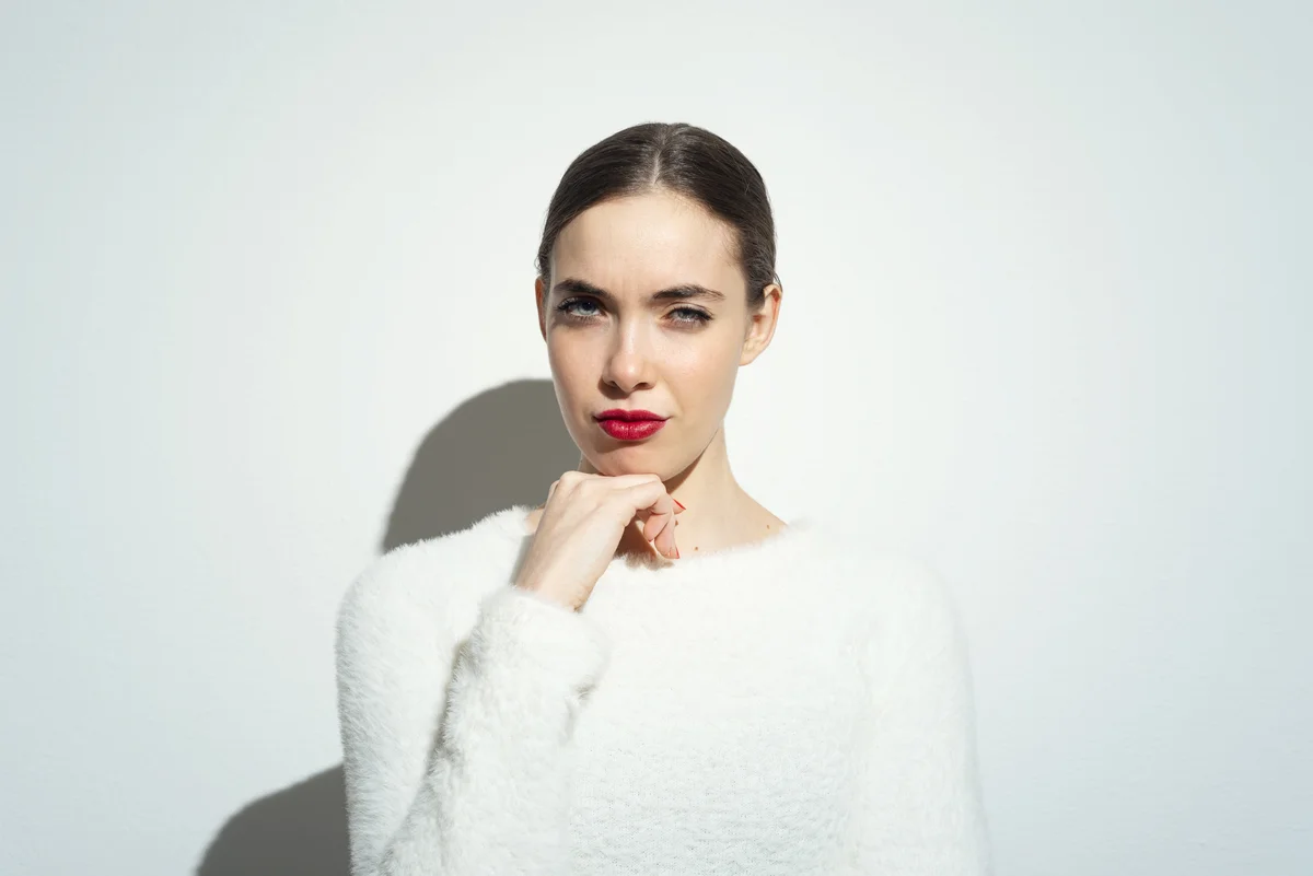 Junge Frau mit roten Lippen im weißen Pullover