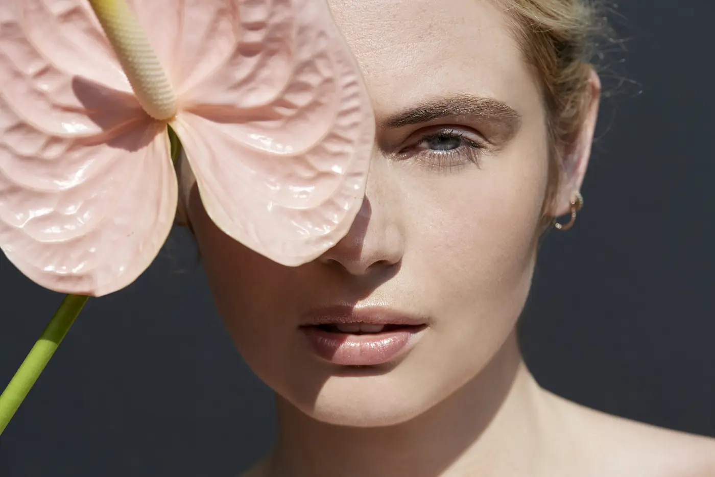 Frau hält tropische rosa Blume vor ihr Gesicht