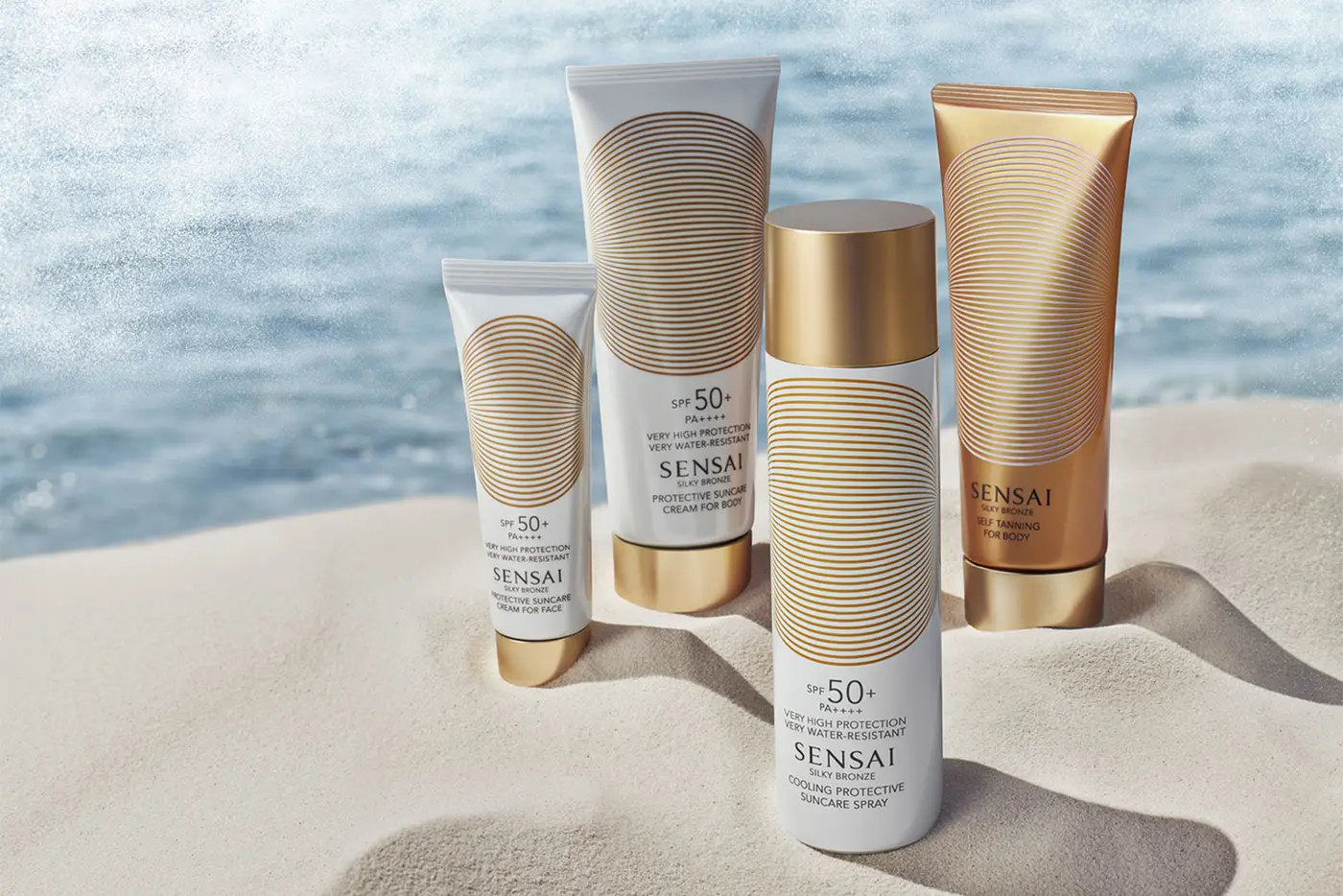 SENSAI Produkte in Nahaufnahme im Sand, im Hintergrund das Meer