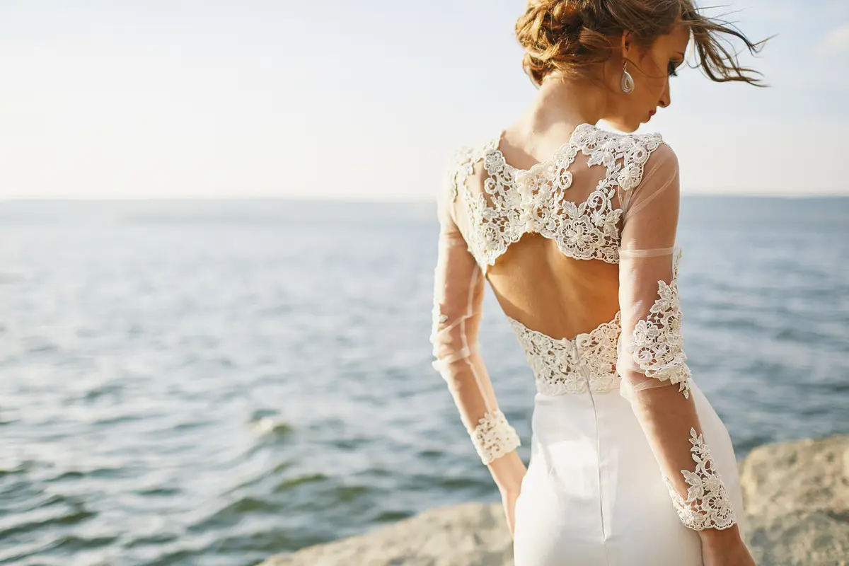 Eine Frau im Brautkleid steht an der Küste