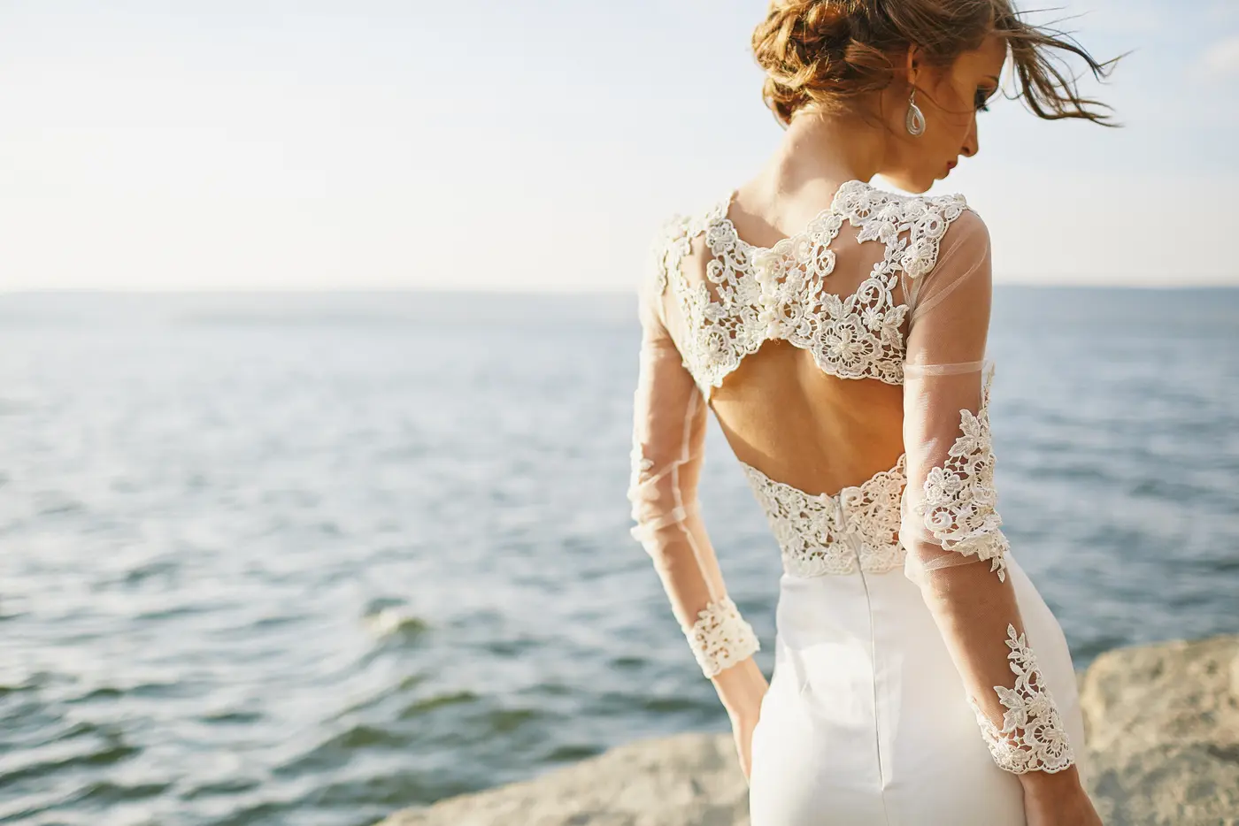 Eine Frau im Brautkleid steht an der Küste