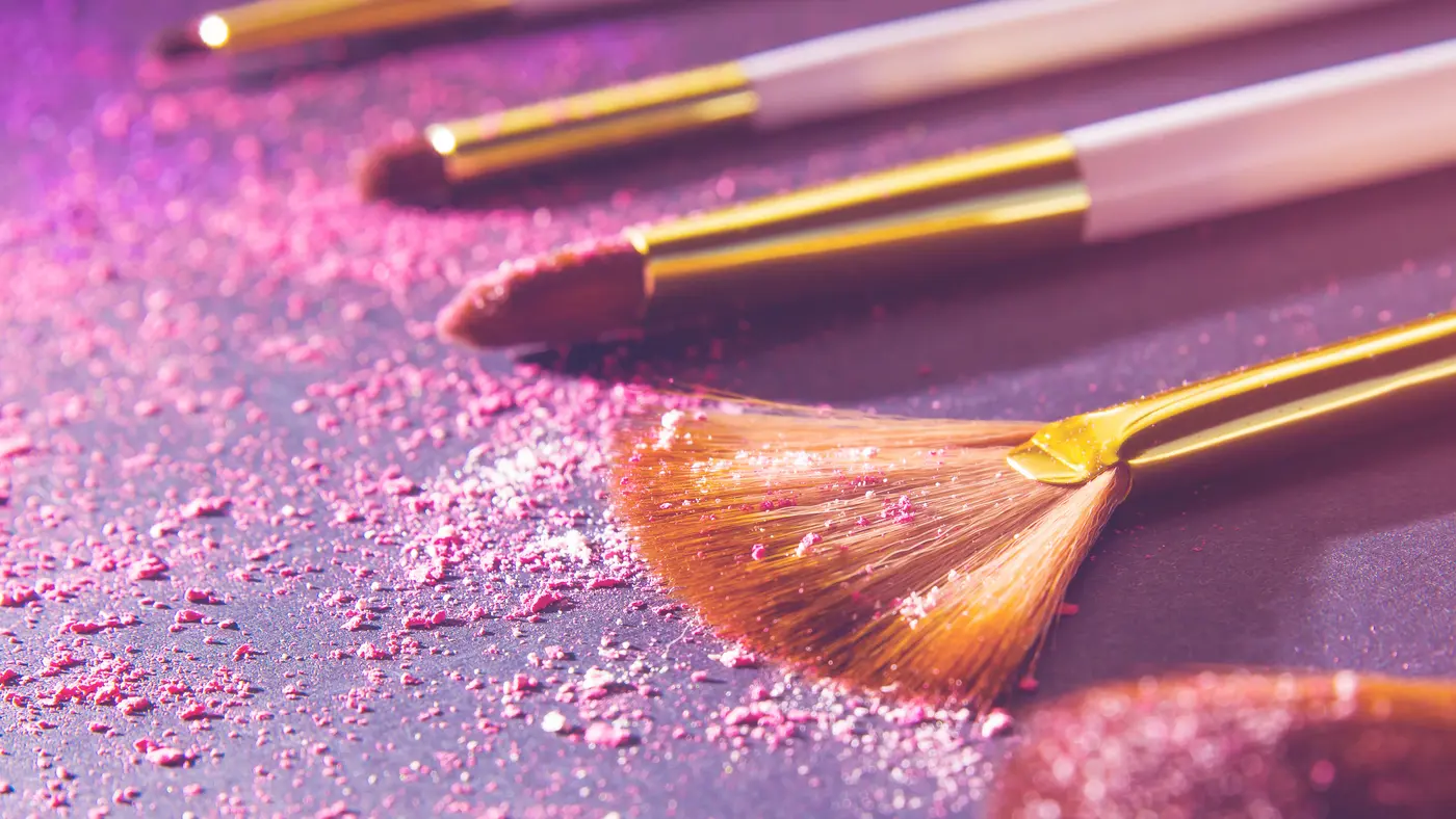 Make-up Pinsel liegen in rosa Puder auf einem Tisch