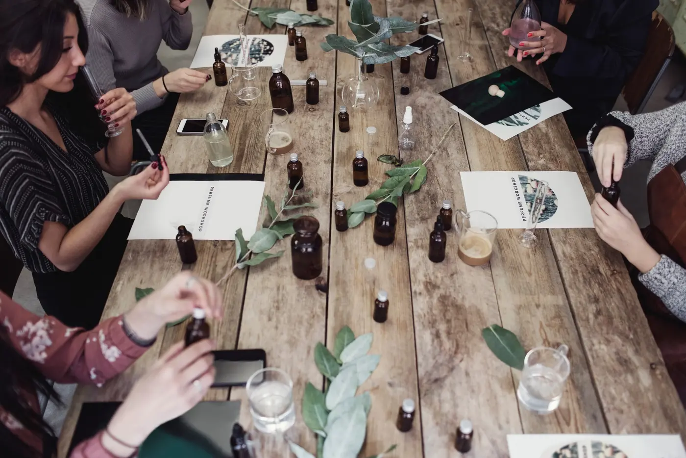 Frauen sitzen an einem Tisch mit Duftölen bei einem Parfum-Workshop