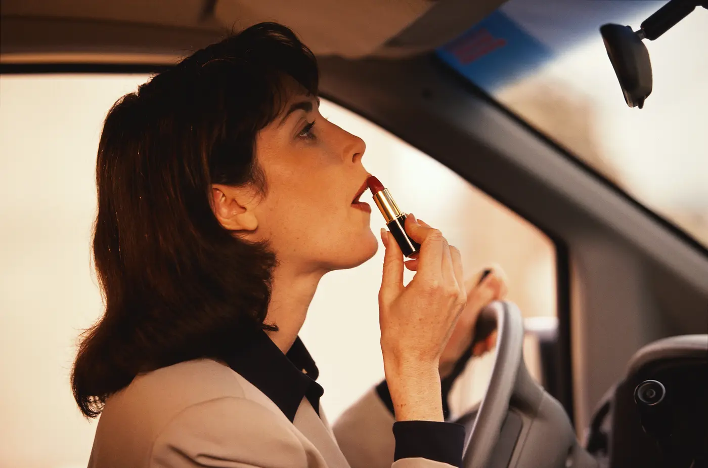Frau im Auto, die sich Lippenstift aufträgt