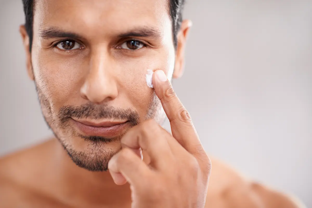 Mann verteilt Lotion auf seiner Wange