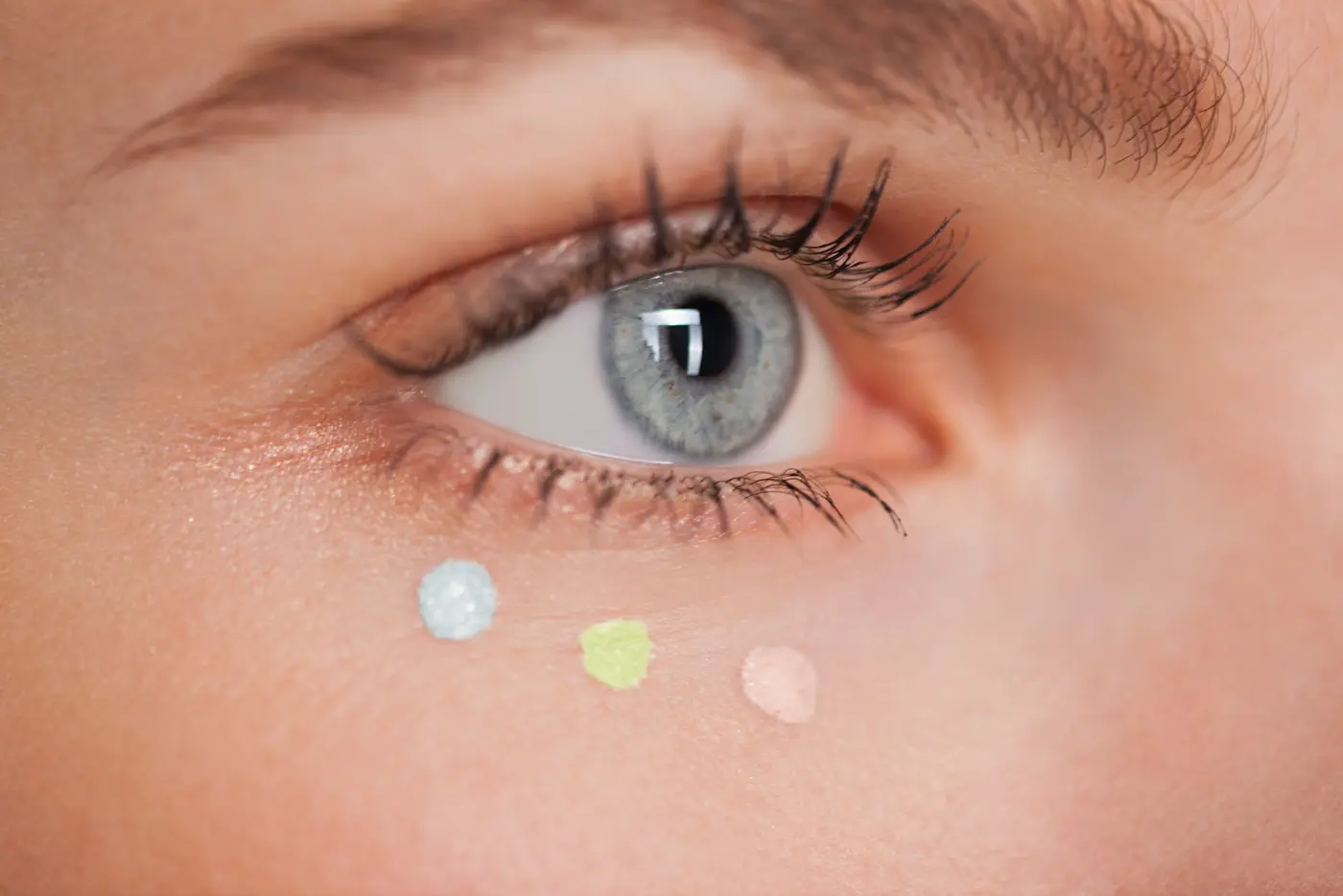 Auge Close-up mit drei Concealer Punkten darunter