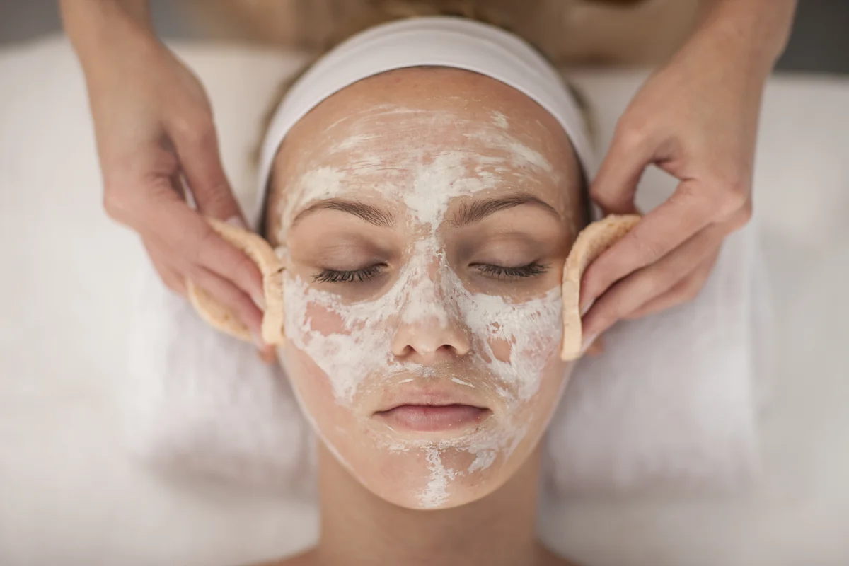 Junge Frau im Spa lässt Gesichtsmaske abtragen